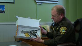 A Sheriff presenting a gun in Netflix's I Am A Killer.