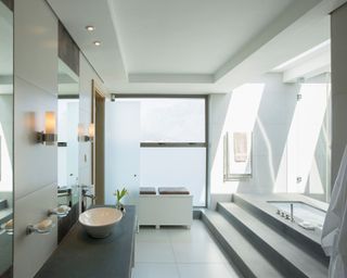 A modern bathroom with a tray ceiling and large windows
