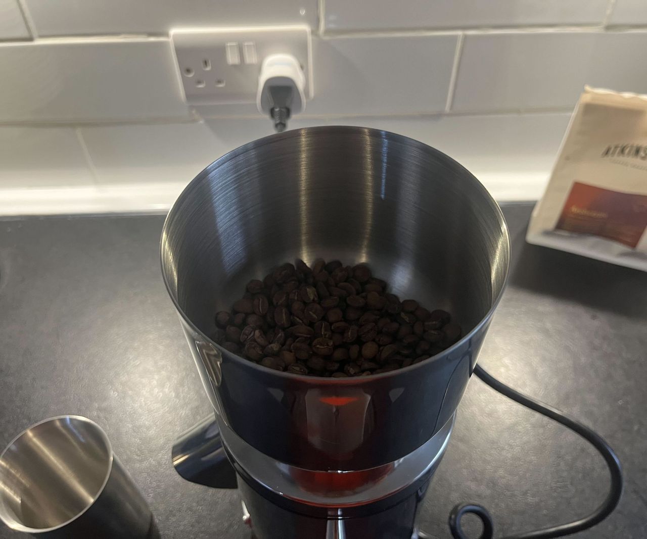 A close up image of coffee beans inside of a stainless steel hopper