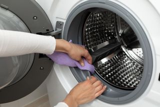 Woman cleaning the seal on a washing machine