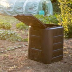 An open black composter in a garden