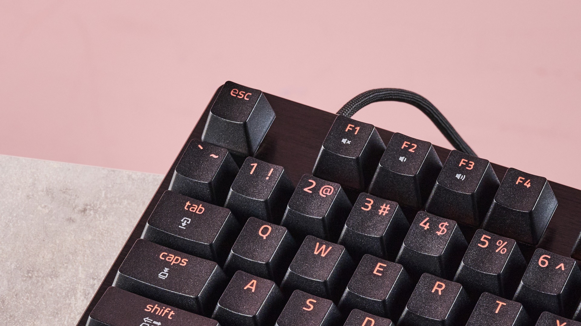 Close-up of top-left keys on Razer Huntsman V3 Tenkeyless 8KHz, on a desk with pink wall in background