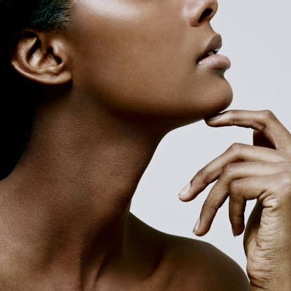 A woman with smooth skin resting her chin on her hand