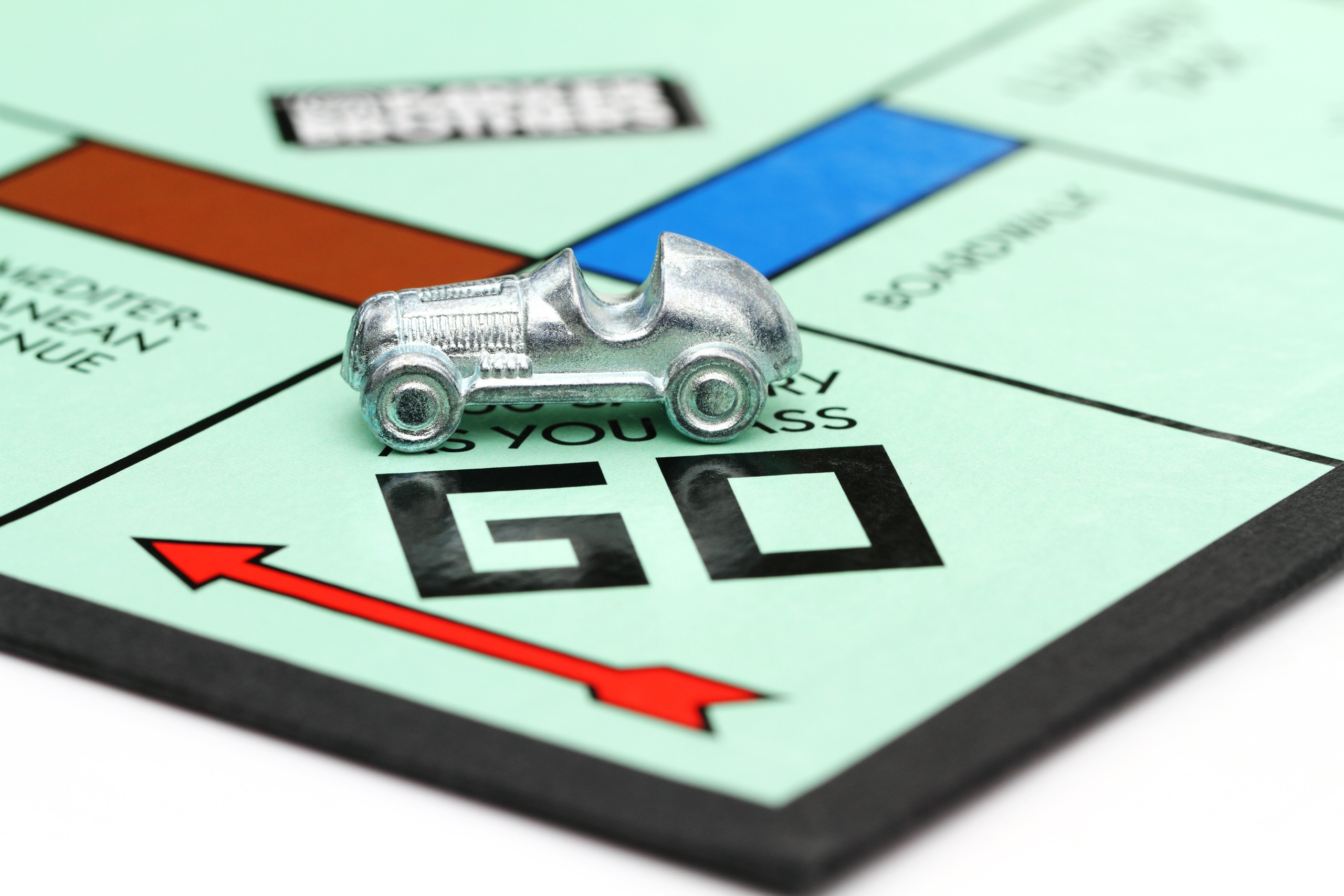 Silver car over the 'go' square of a Monopoly board.