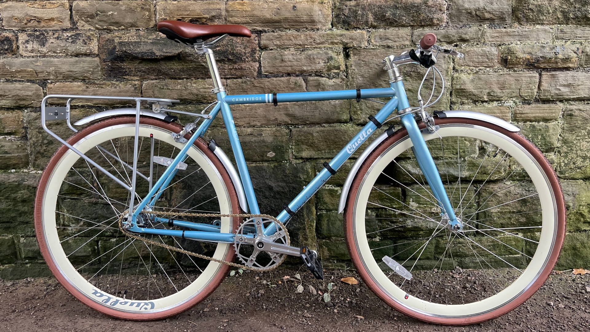The Quella Varsity Cambridge in baby blue leaning up against a stone wall