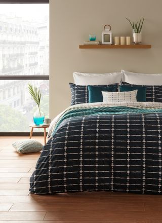 Deep blue patterned bedsheets with white and teal pillows