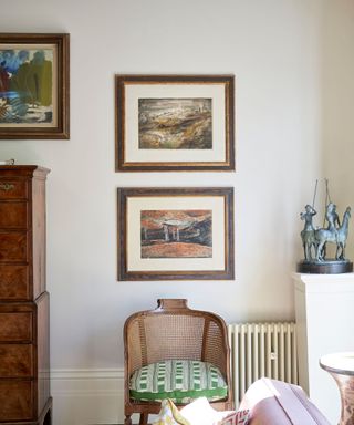 A light gray room with a small chair and framed artwork