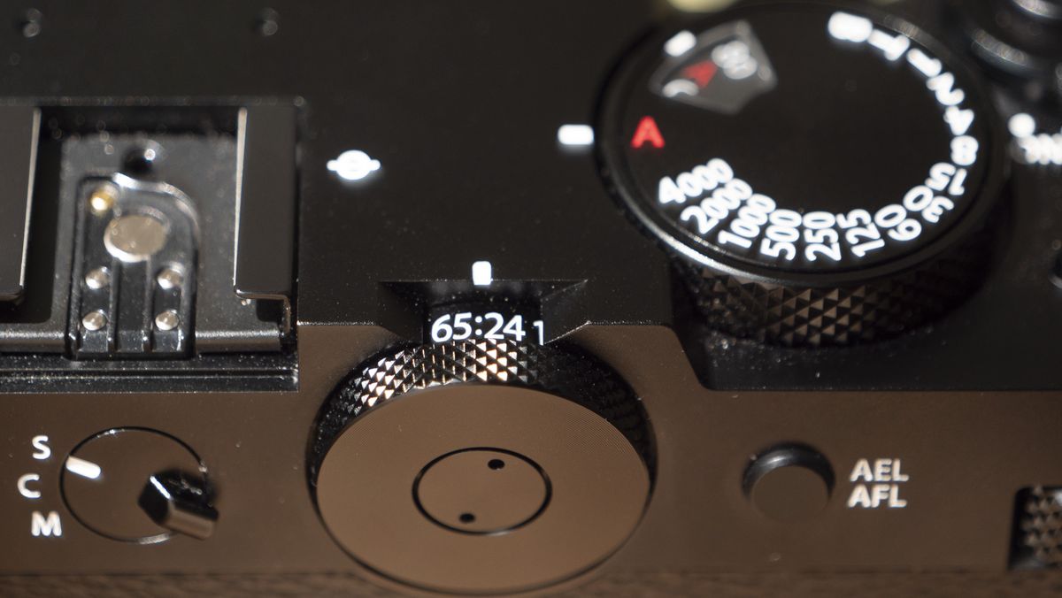 All-black Fujifilm GFX100RF rangefinder-style camera on a wooden table
