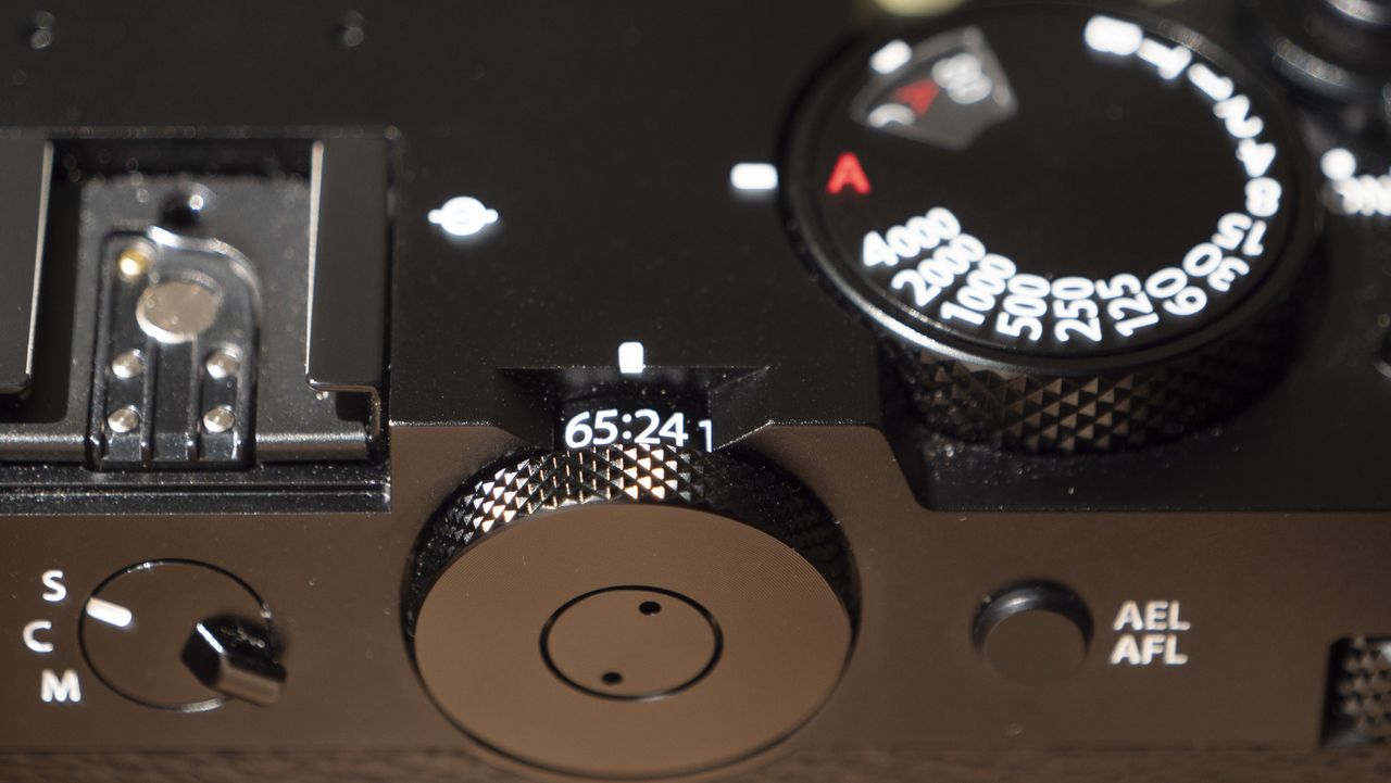All-black Fujifilm GFX100RF rangefinder-style camera on a wooden table