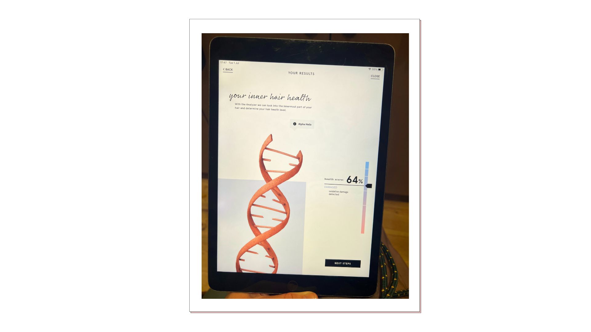 An ipad with a screen showing a hair health scan results page, which lists 64% as the overall hair health score