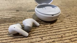 LG Tone Free T90Q earbuds on a wooden table