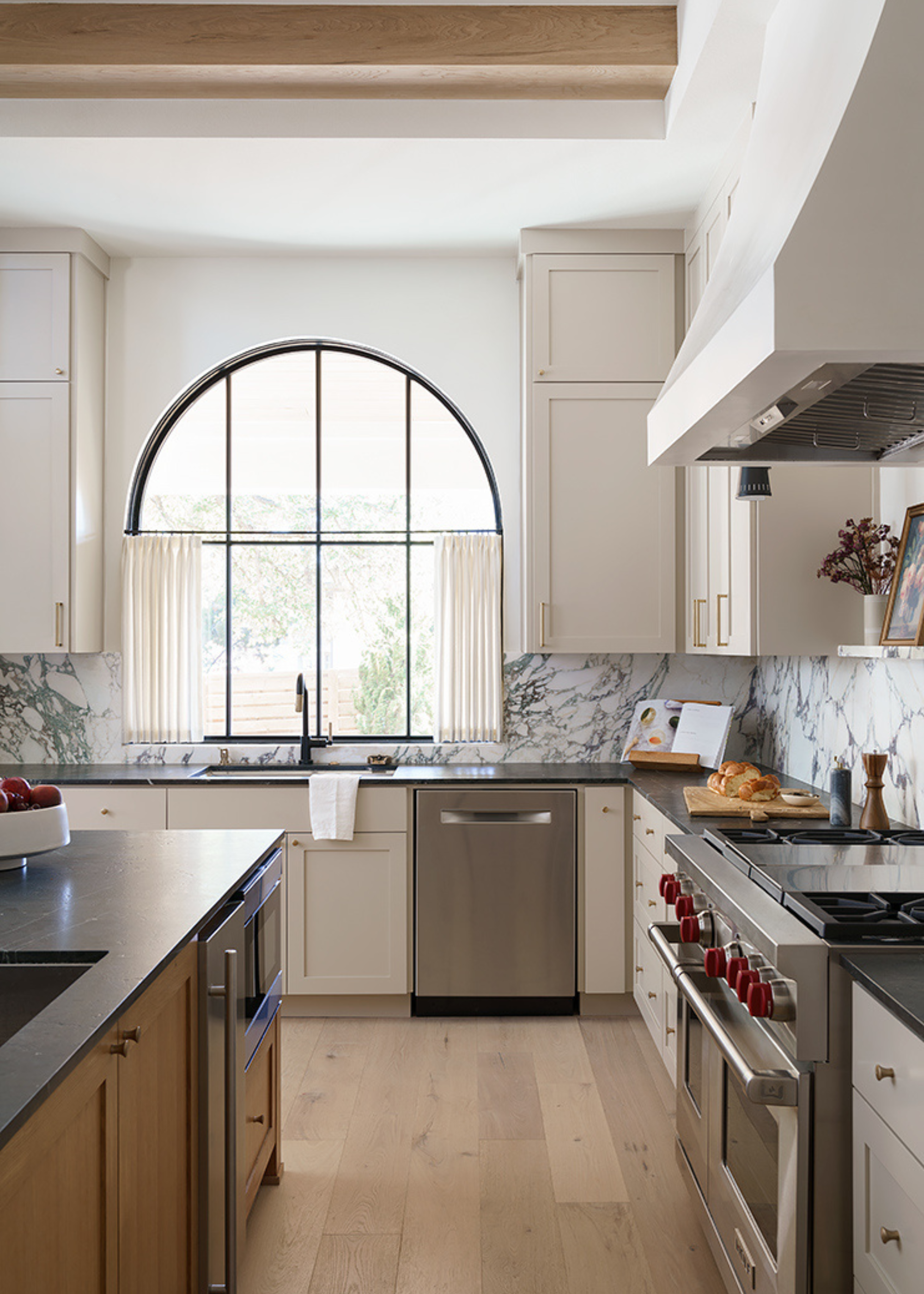 bright, traditional kitchen with large arched window and cafe curtains