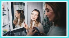 Happy female friends with mobile phone and lip gloss at dorm bathroom, dorm bathroom essentials