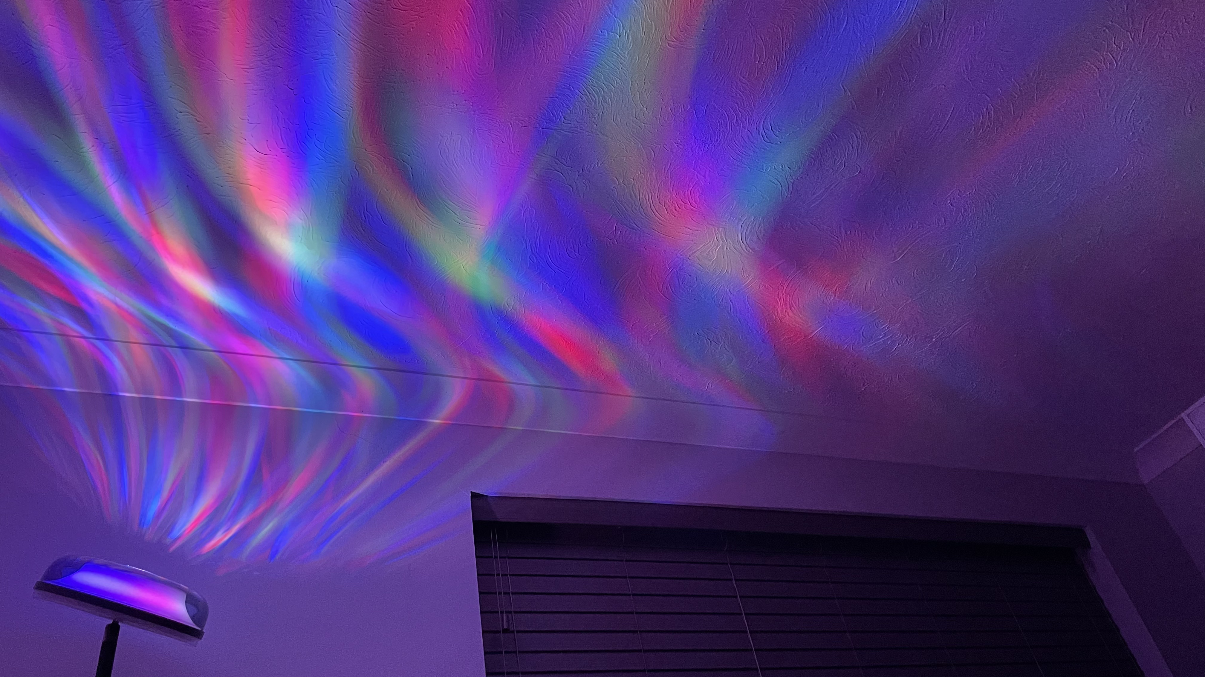 The Govee Uplighter Floor Lamp is projecting an aurora borealis effect onto a bedroom ceiling.