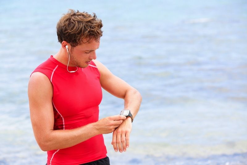 A man pauses during a workout to check his watch.