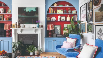 A living room painted in white with arched alcove bookcases painted in a sky blue with a warm red interior