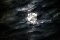 A bright silver sphere shrouded by black smoke