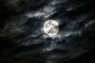 A bright silver sphere shrouded by black smoke