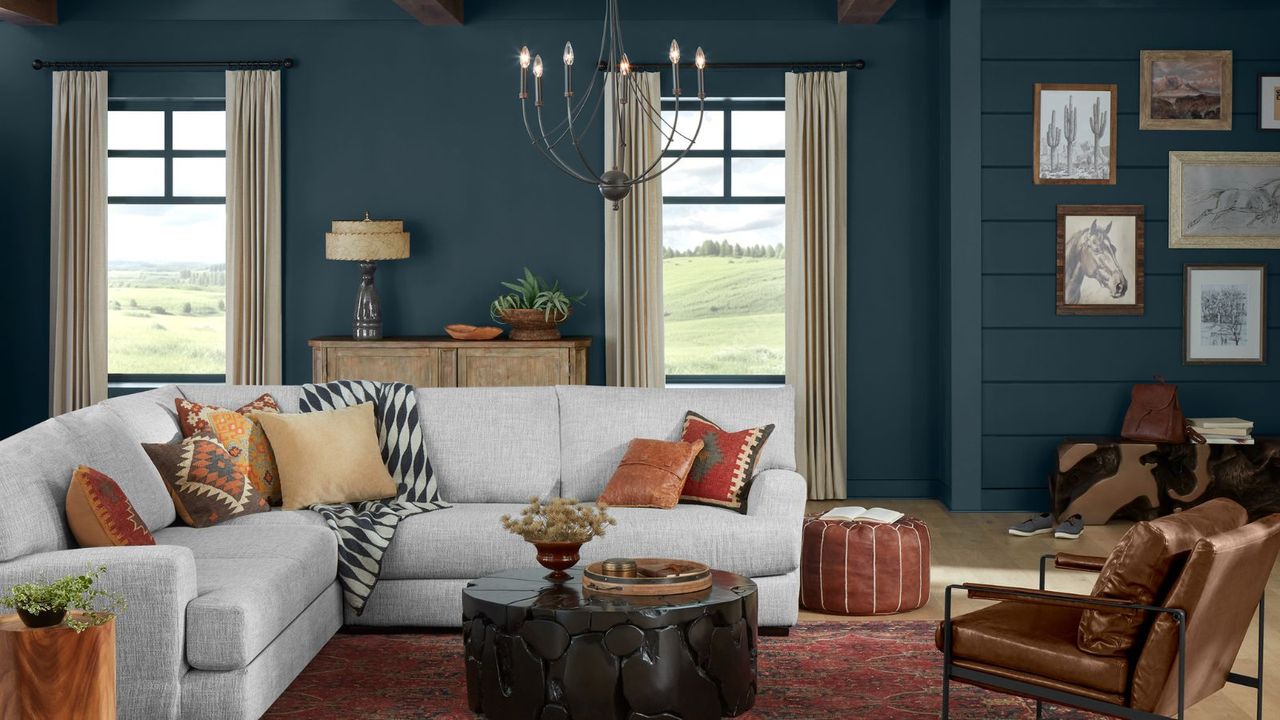 living room with dark blue walls, gray corner sofa, cozy rustic decor