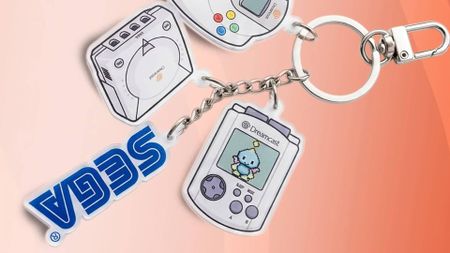 Sega Dreamcvast keychain set with VMU, Sega logo, Dreamcast console, and controller on orange backdrop.