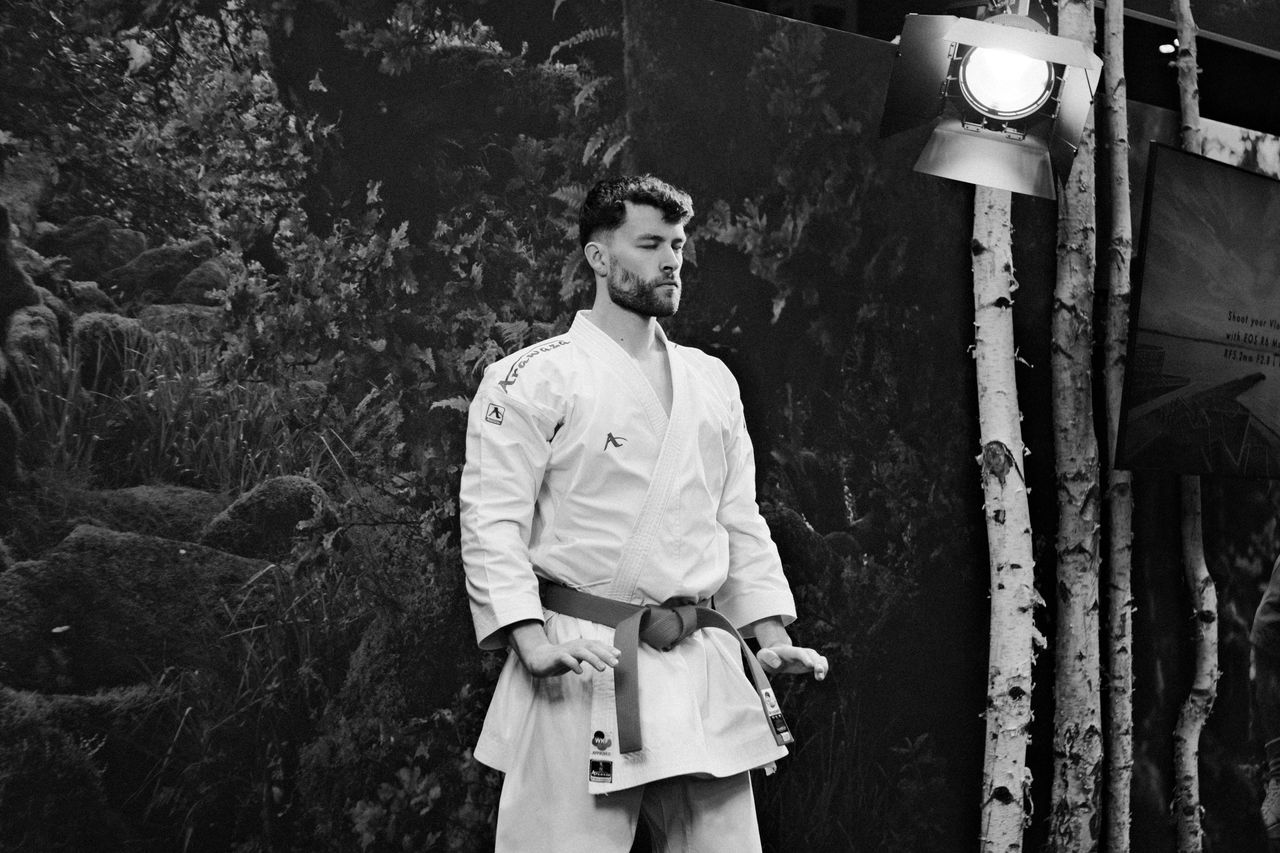 Man in a martial arts uniform posing under studio lights