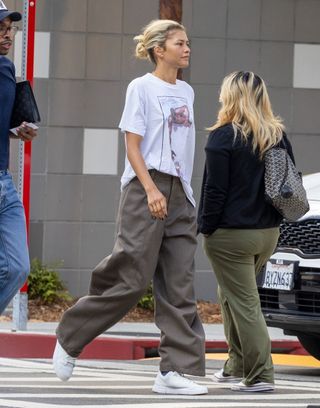 A photo of Zendaya wearing a rare vintage tee and baggy brown trousers.