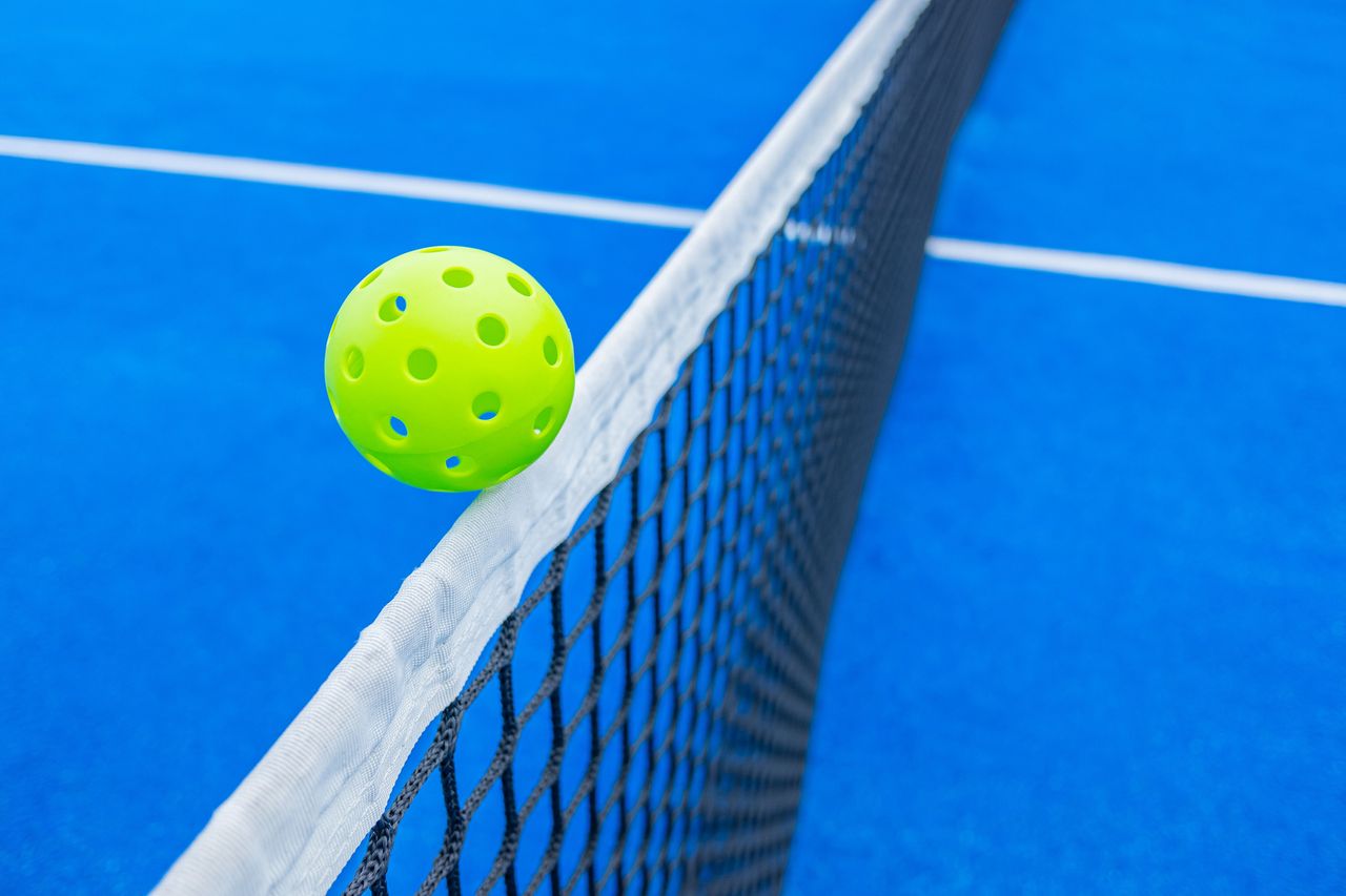 pickleball on the edge of a court net