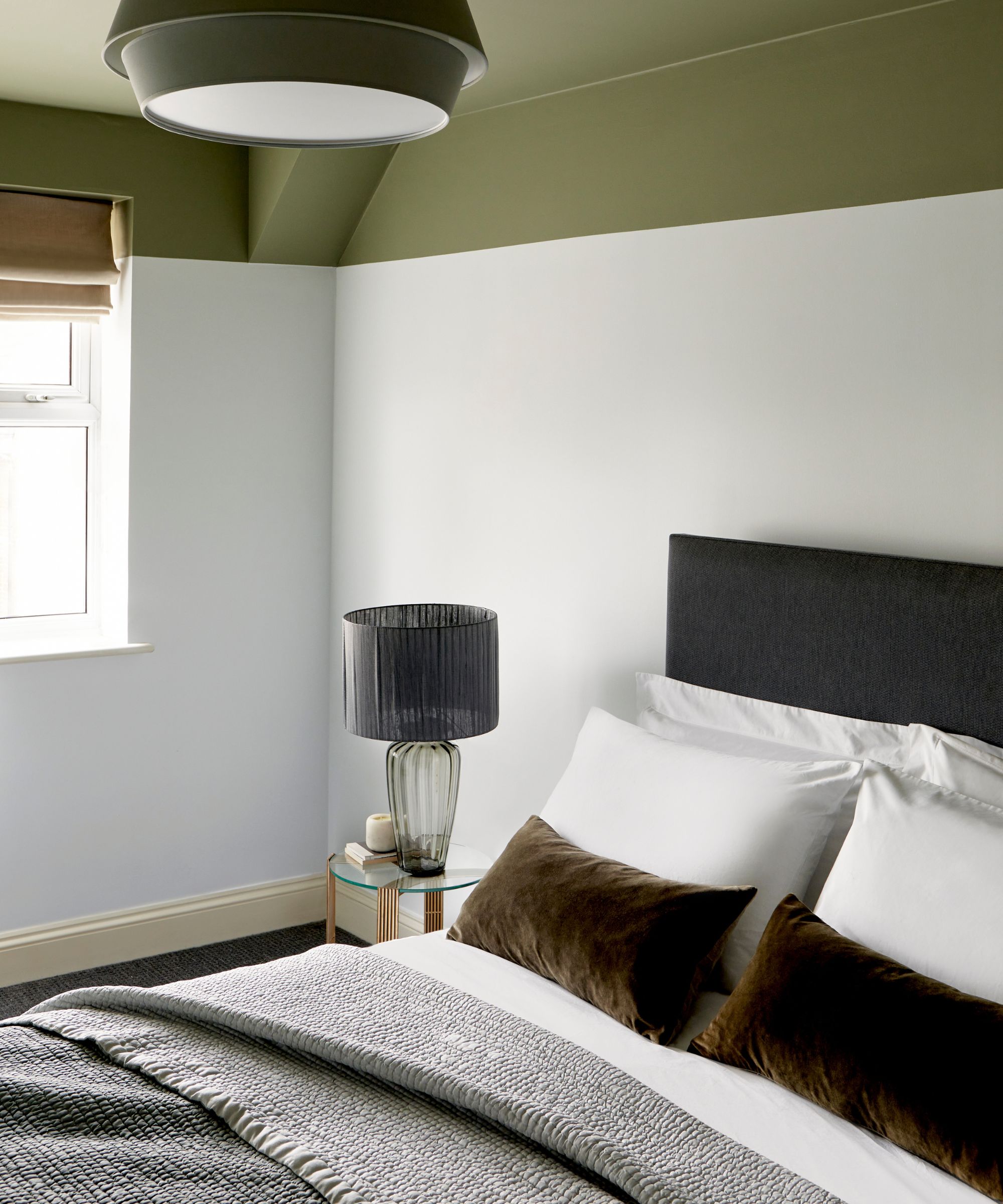 white painted bedroom with an olive green accent ceiling and soft green painted skirting with a dark green bed with white linens and olive velvet throw pillows