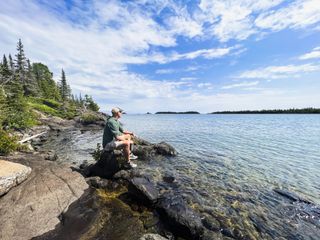 A man sits on the rocky shoreline of Lake Superior in Michigan's Isle Royale National Park