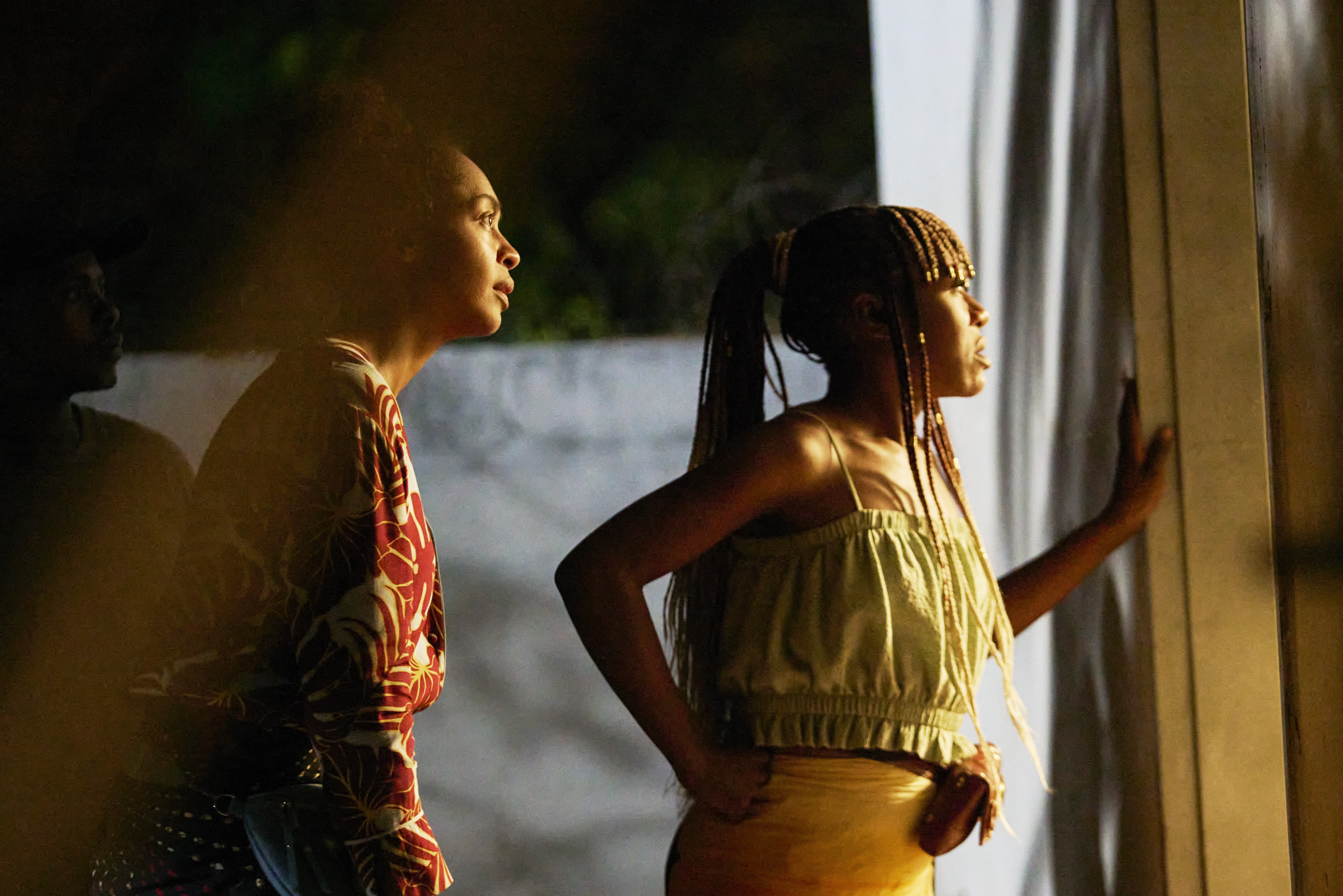 Susan Chardy as Shula and Elizabeth Chisela as Nsansa, looking out a window, in 'On Becoming a Guinea Fowl.'