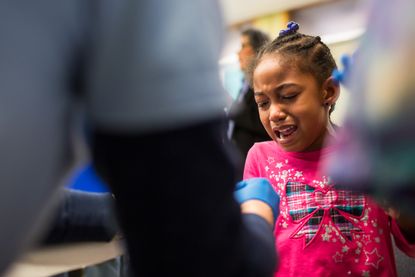 A girl cries as she gets her finger pricked for a lead screening in Flint, Michigan.