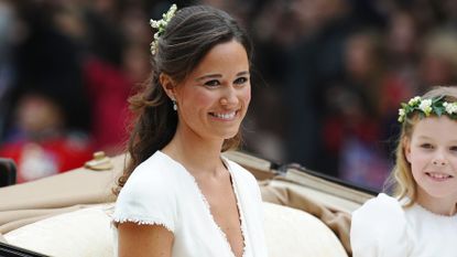 Pippa Middleton smiles at the crowd from the back of a horse drawn carriage.