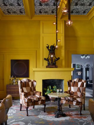 bright yellow walls in room with fireplace and armchairs