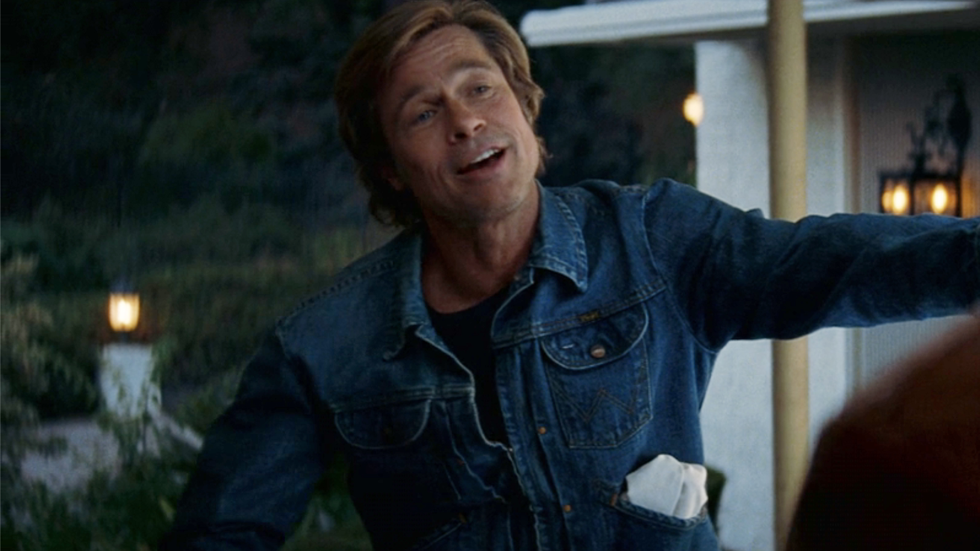 Cliff Booth (Pitt), dressed head to toe in denim, stands outside Ricks door at night in Once Upon a Time in Hollywood (2019).