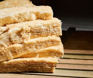 Thick layers of fiberglass insulation piled up on a wooden floor