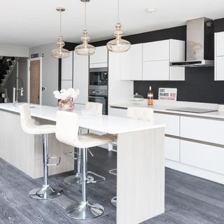 kitchen with white counter white bar chairs white cabinet and grey wooden flooring