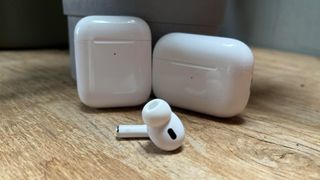 A single AirPod in front of two cases