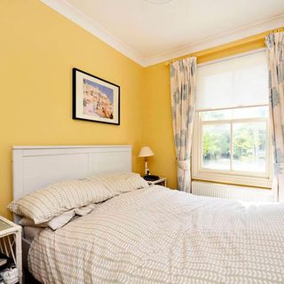 bedroom with yellow wall with white window