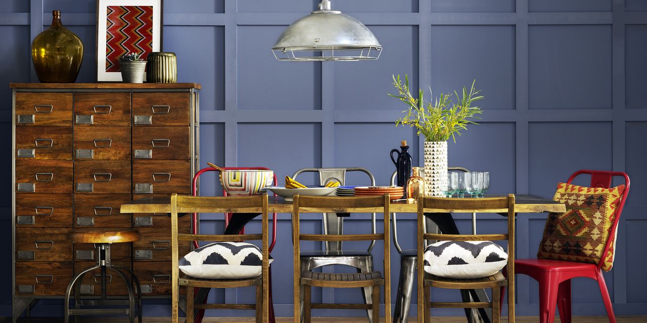 A dark wood cabinet and dark wood kitchen table sat against a blue panelled wall and styled with accents of red