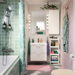 A pink and green bathroom with green shower tiles