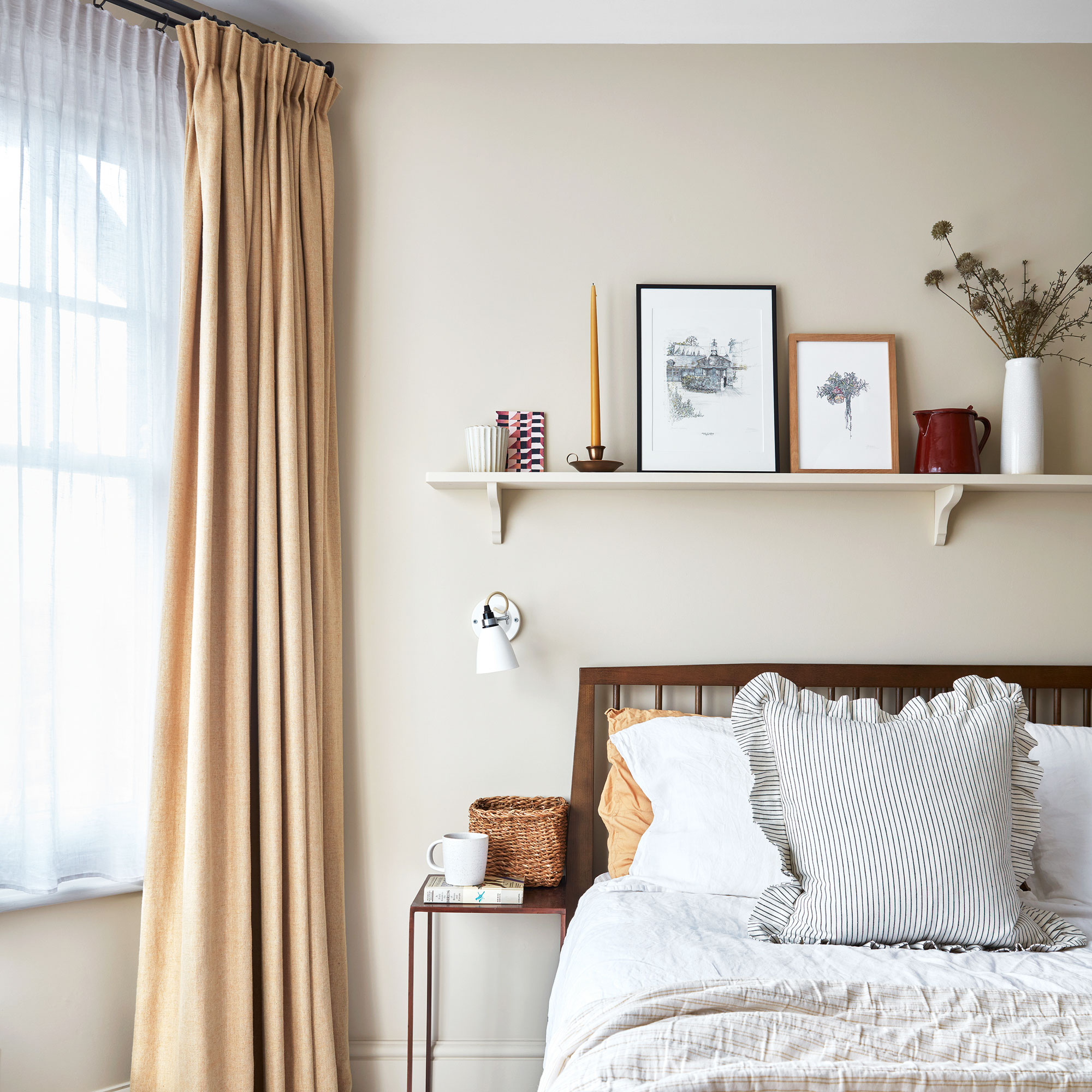 Cream walls with voile and yellow curtains, wooden bed and shelf