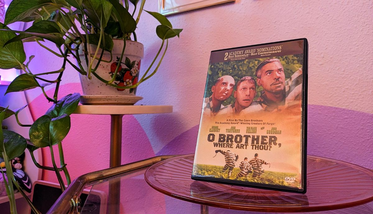A DVD of O Brother, Where Art Thou? next to a pothos and a pink and purple painted wall