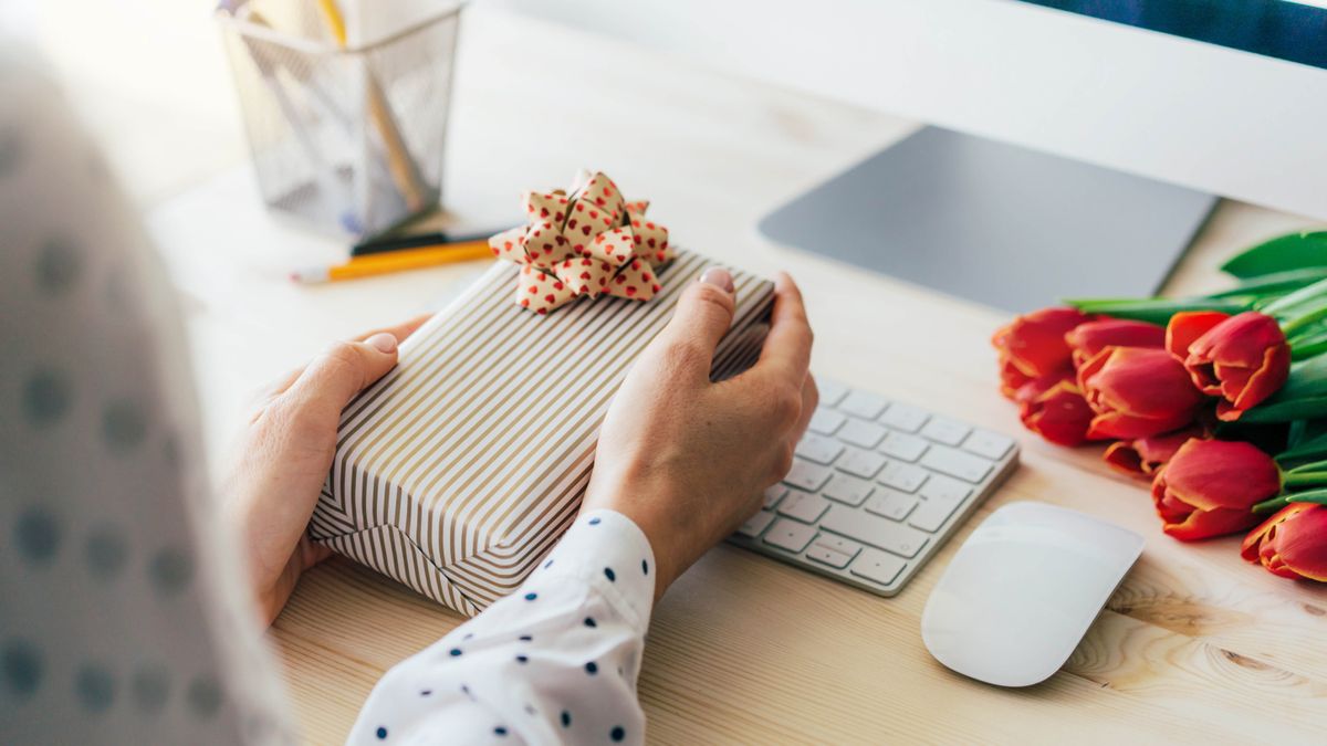 Someone holding a present in front of a computer