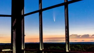 a comet streaks the sky above a dark forest seen through empty windows high up