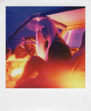 Polaroid photo of young woman getting out of car
