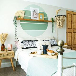 Bedroom with green painted circle feature wall and white bedstead