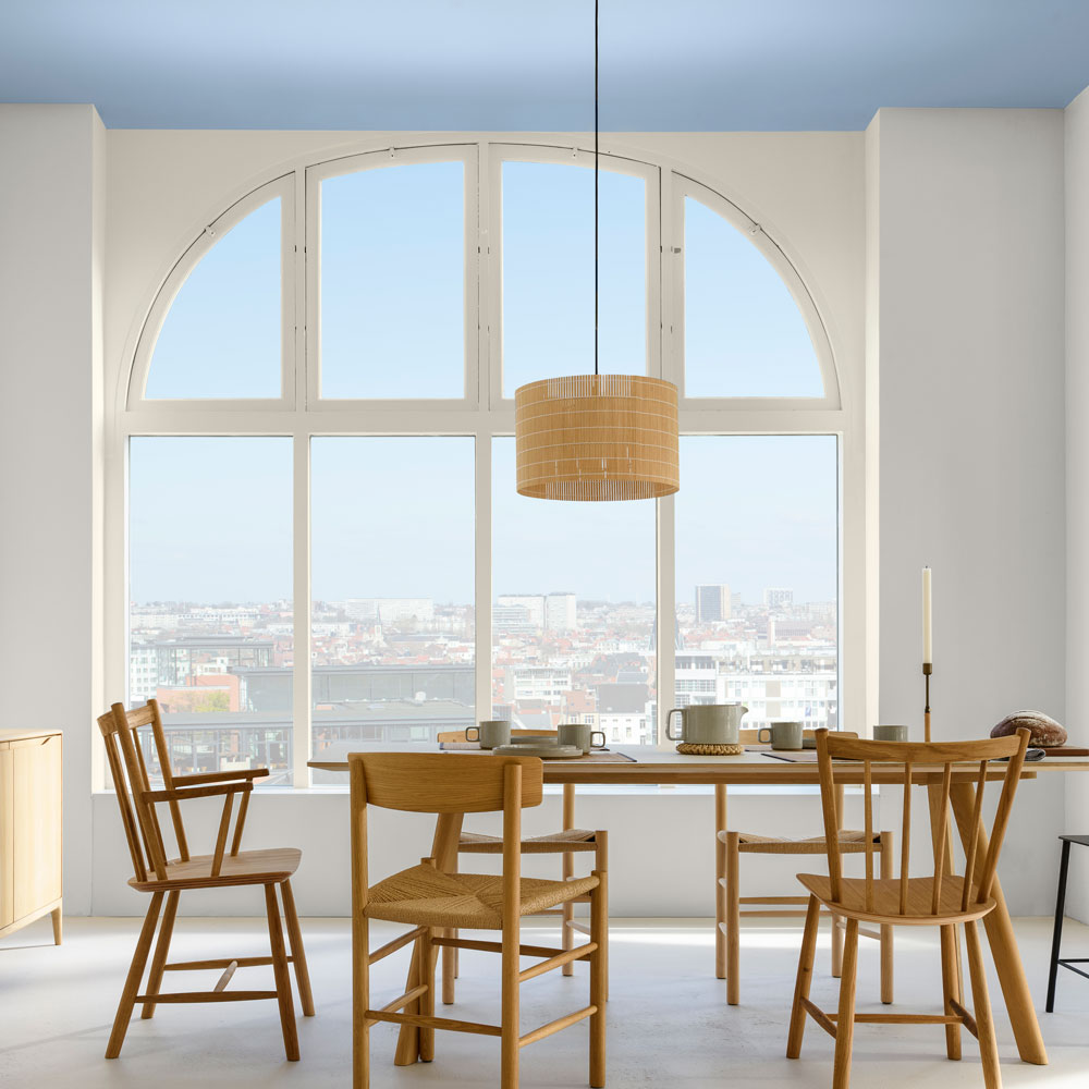 A light and spacious kitchen, low hanging light above the wooden dinning table