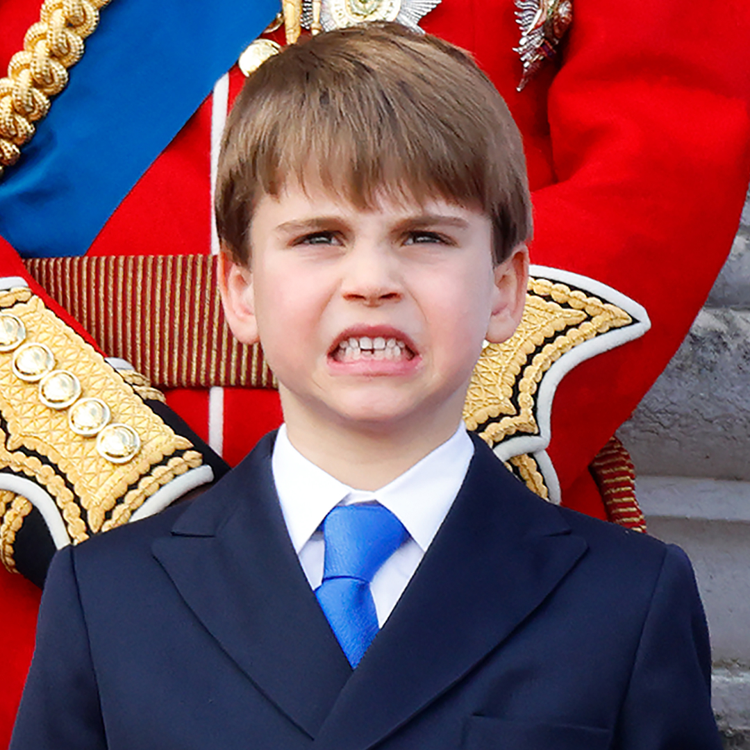 Prince Louis stands on the Buckingham Palace balcony wearing a navy suit with a white shirt and royal blue tie