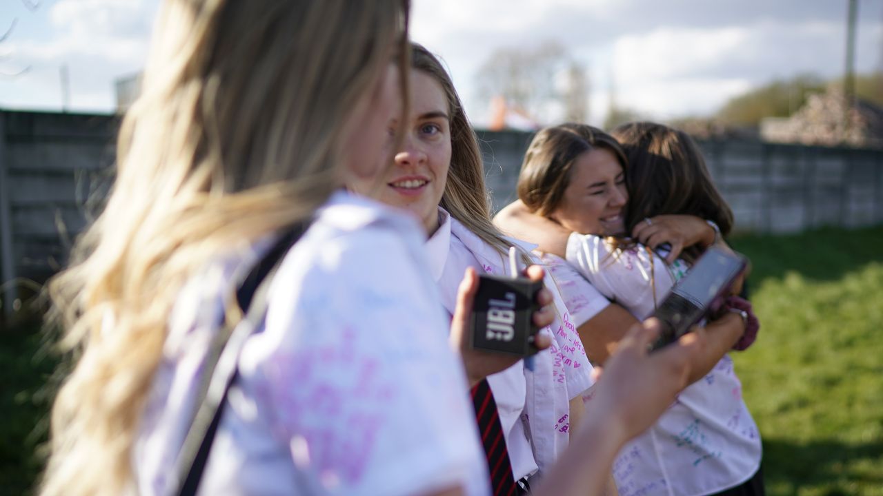 Senior schoolchildren hug outside their school