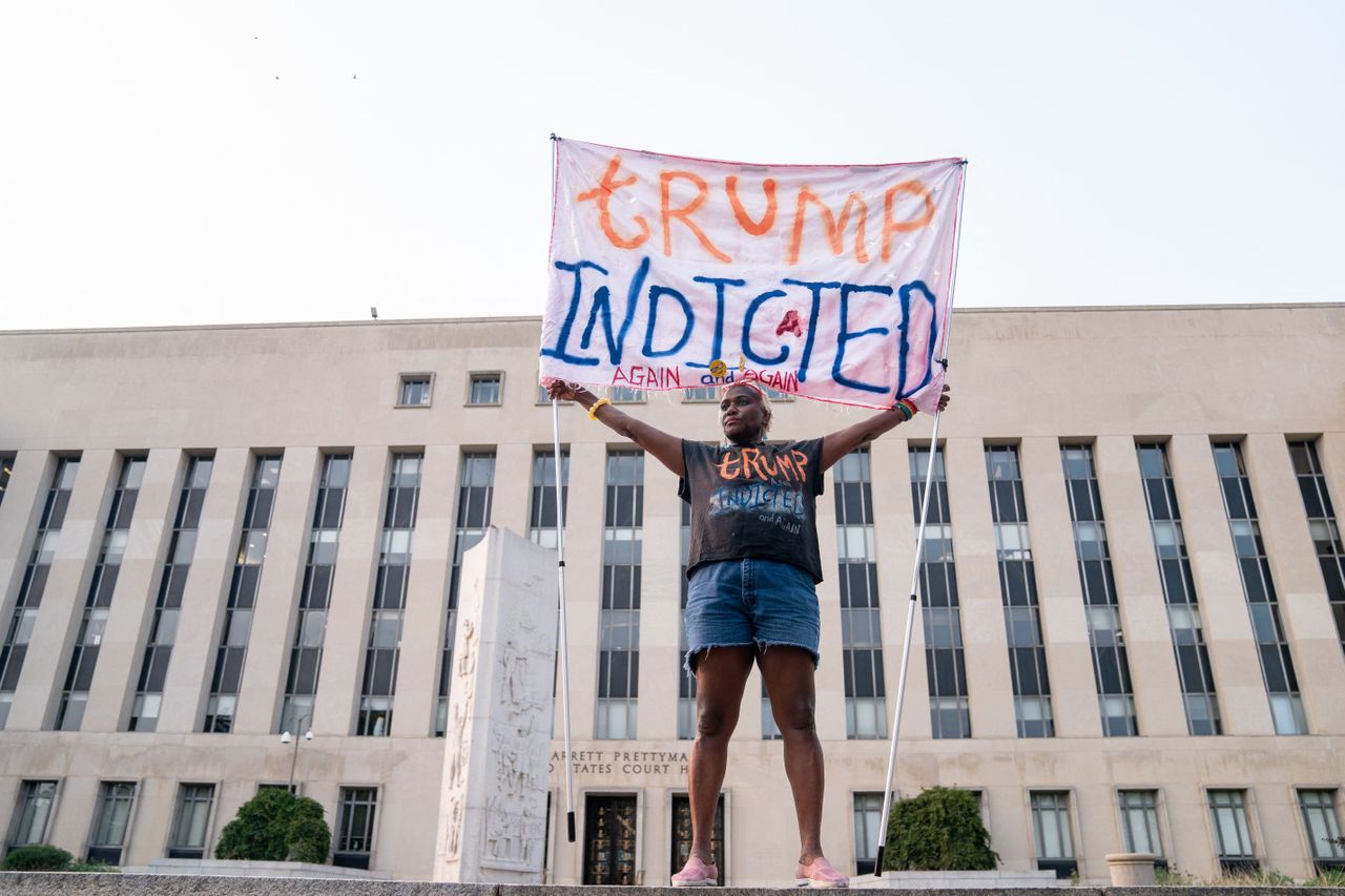 A person holds a sign reading &amp;quot;Trump Indicted&amp;quot; 